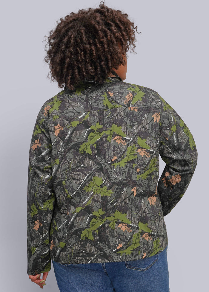1X=A person shown from the back wearing a camouflage jacket with green, gray, and brown woodland print, paired with blue jeans, against a solid gray studio background.