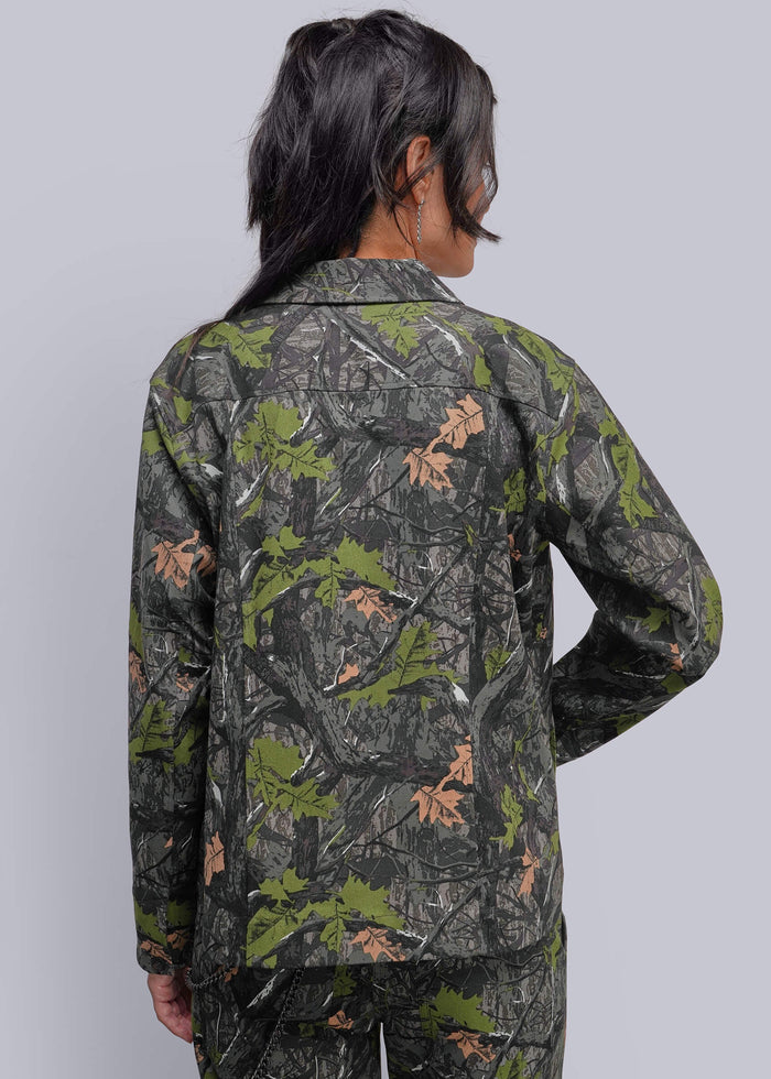 S=A model shown from the back wearing a long-sleeve jacket and matching pants in a dark green, brown, and black woodland camouflage pattern with brown leaf accents, set against a solid light gray background.