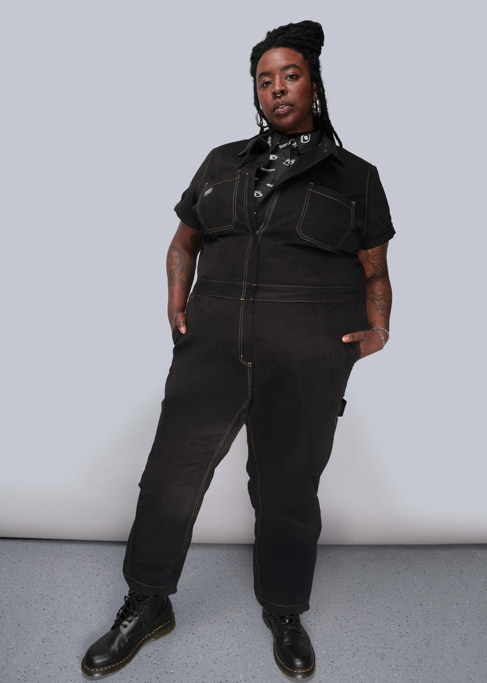 1X=Person wearing a black jumpsuit against a plain background