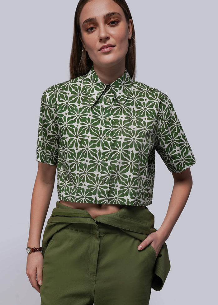 S=Person wearing a green patterned shirt and green pants against a plain background