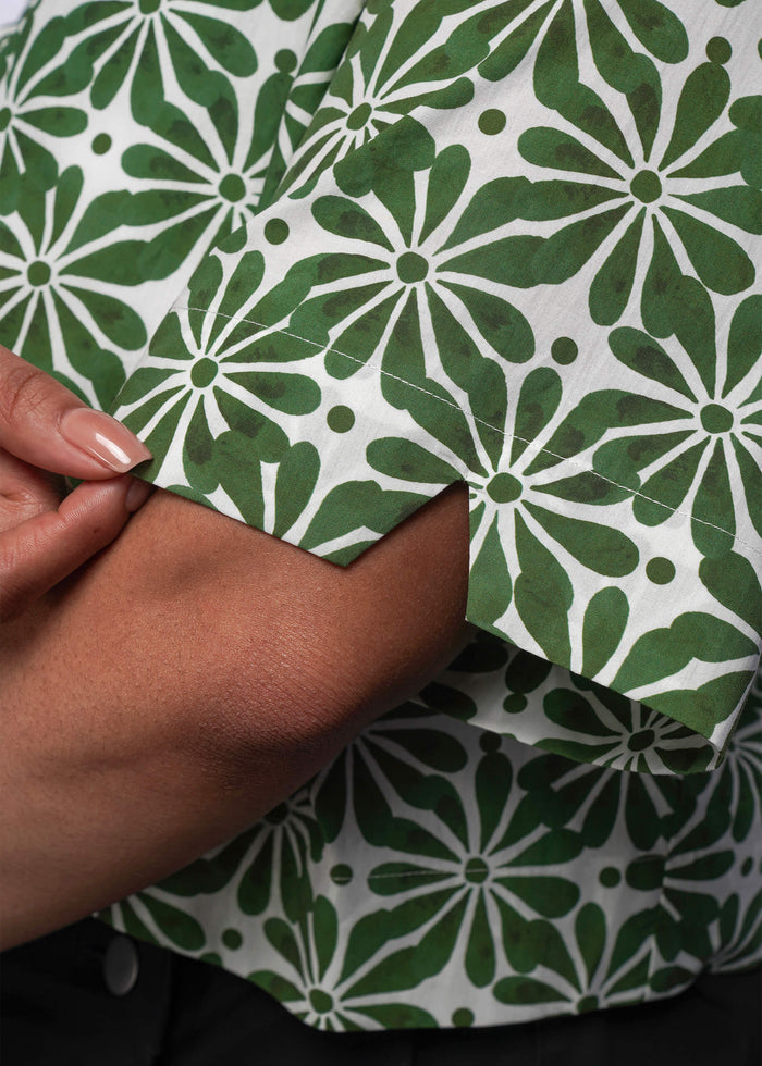 1X=Close-up of green and white patterned fabric with a hand touching it