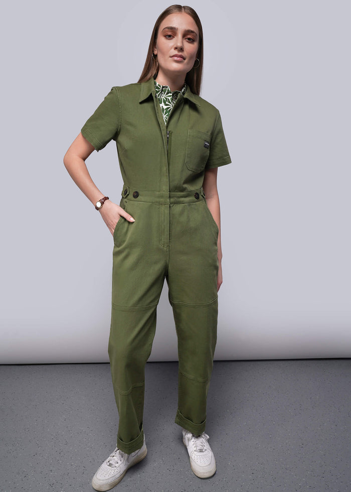 S=Woman wearing a green jumpsuit against a plain background