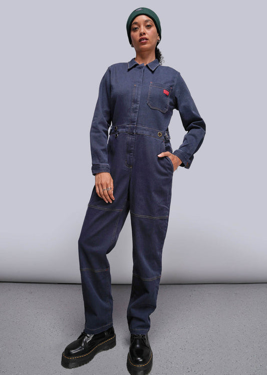 S=Person wearing a navy blue jumpsuit with a red pocket patch on a plain background