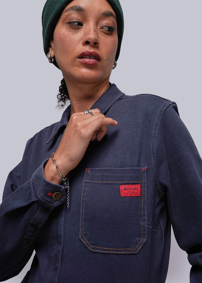 S=Person wearing a navy blue jacket with a red pocket patch on a plain background