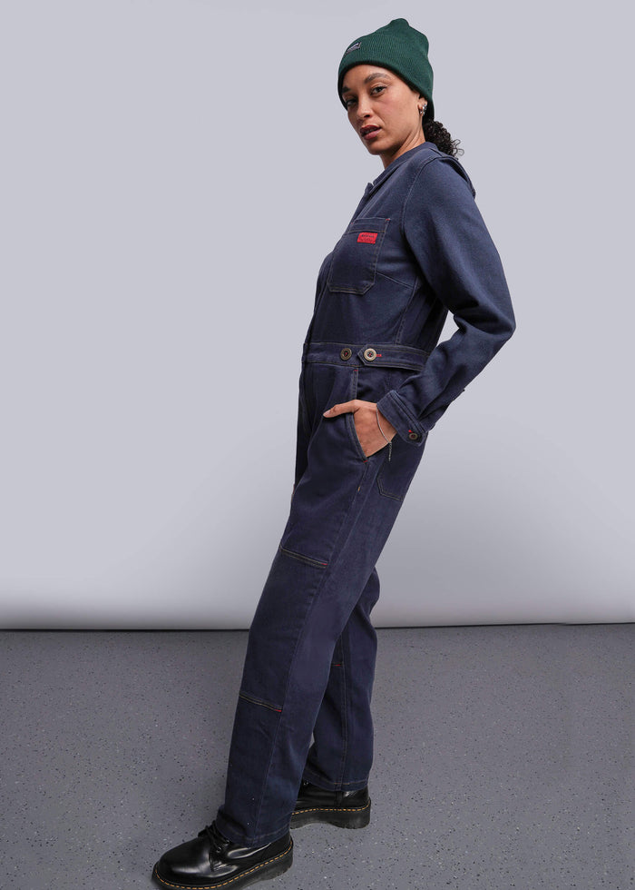 S=Person wearing a navy blue coverall with a green beanie on a plain background