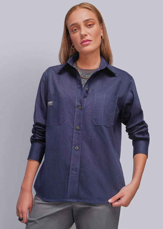 S=A woman modeling a navy blue long-sleeve button-up shirt with chest pockets, paired with gray pants, against a solid gray studio background.