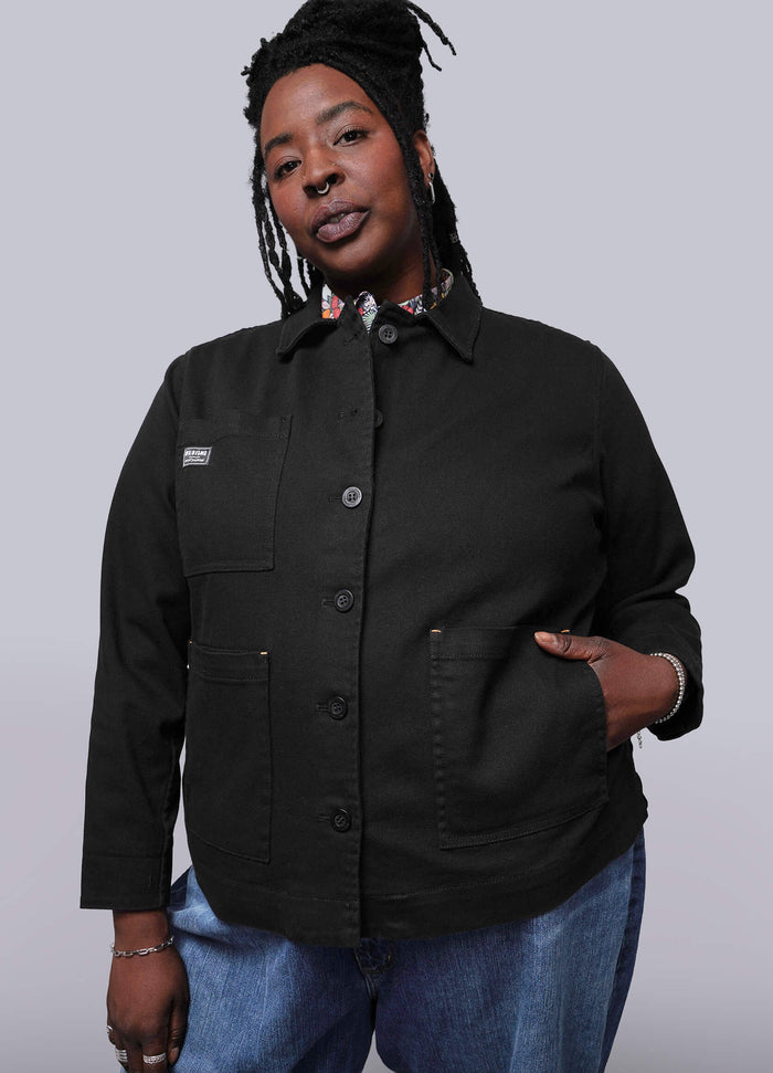 1X=Person wearing a black jacket and blue jeans against a white background