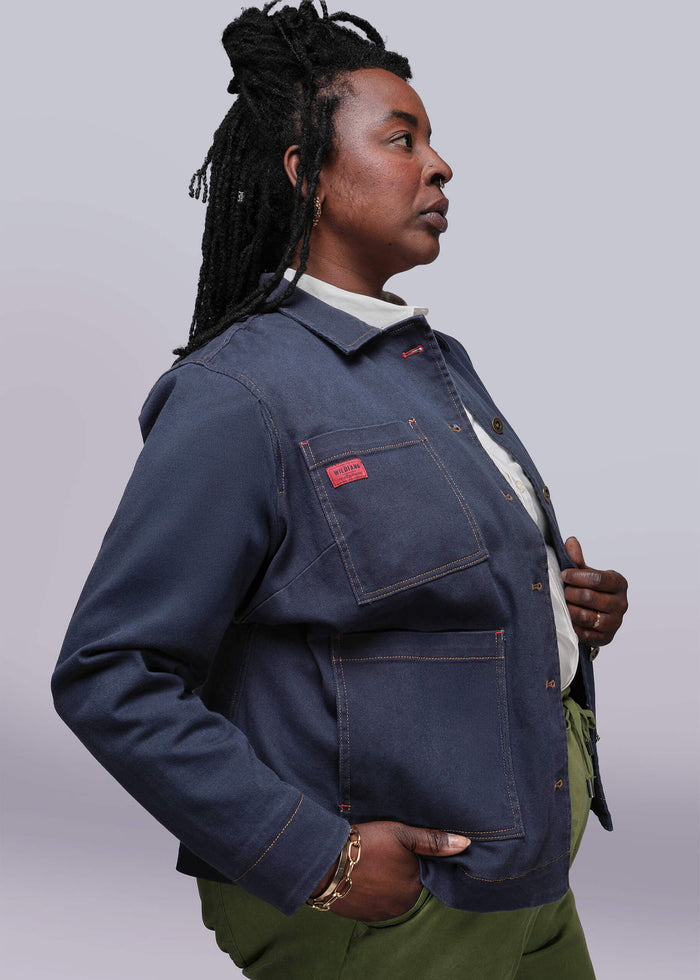 1X=Person wearing a blue denim jacket with a red label on a plain background