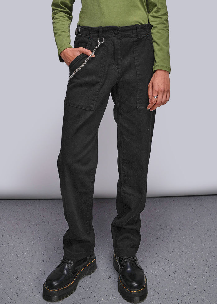 S=Person wearing black pants and green shirt against a plain background