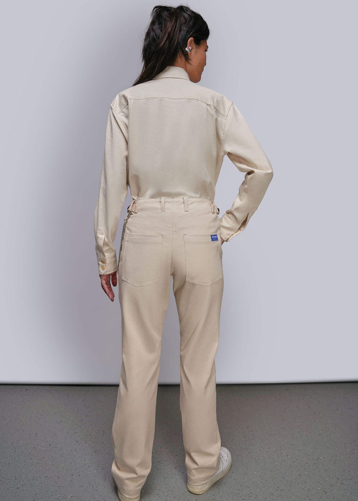 S=A model viewed from the back wearing a matching beige long-sleeve button-up shirt and straight-leg work pants, standing against a light gray studio wall.