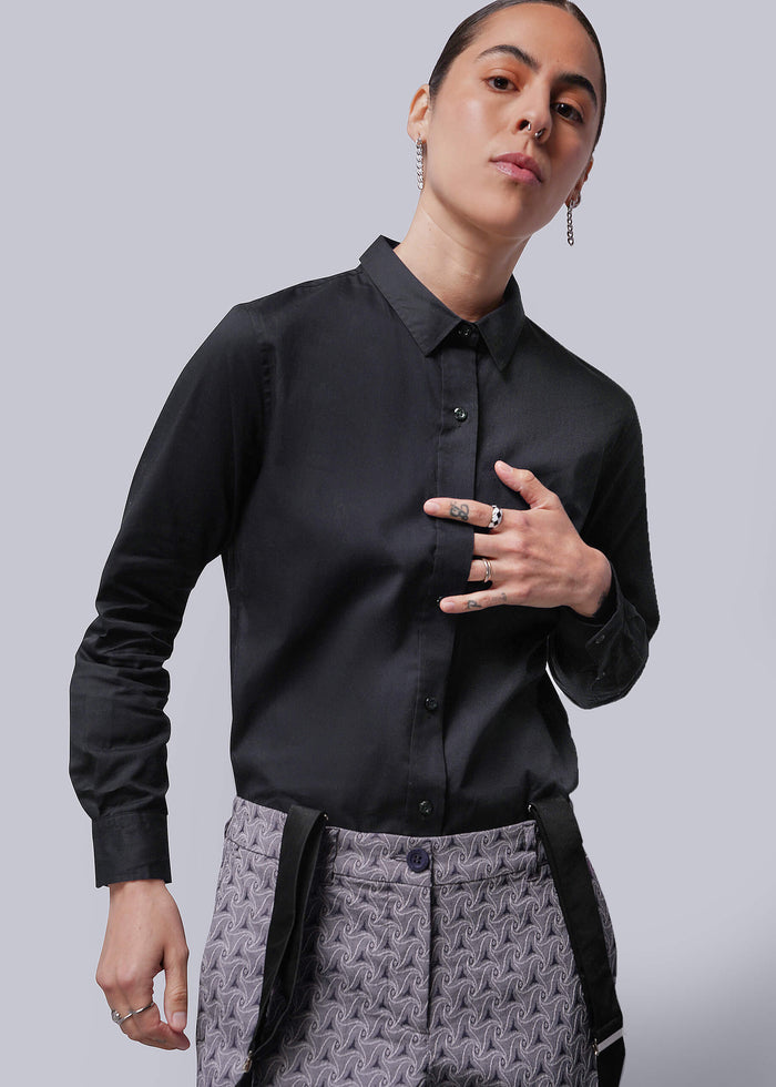 S=Person wearing a black shirt and patterned pants on a plain background
