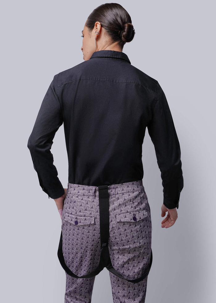 S=Person wearing a black shirt and patterned apron on a gray background