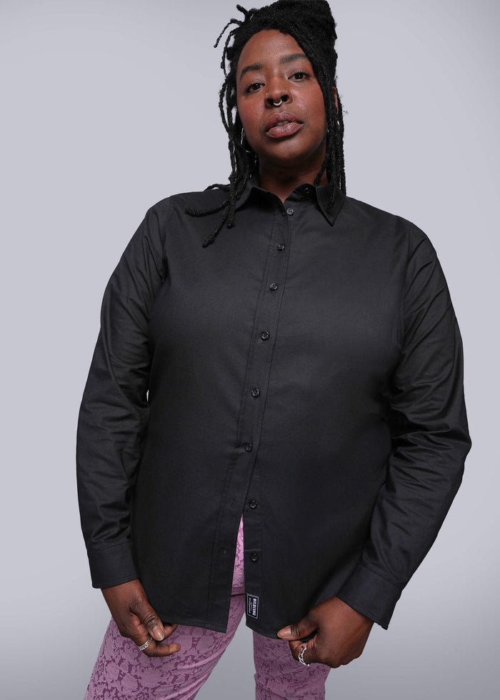 1X=Person wearing a black button-up shirt with a plain background