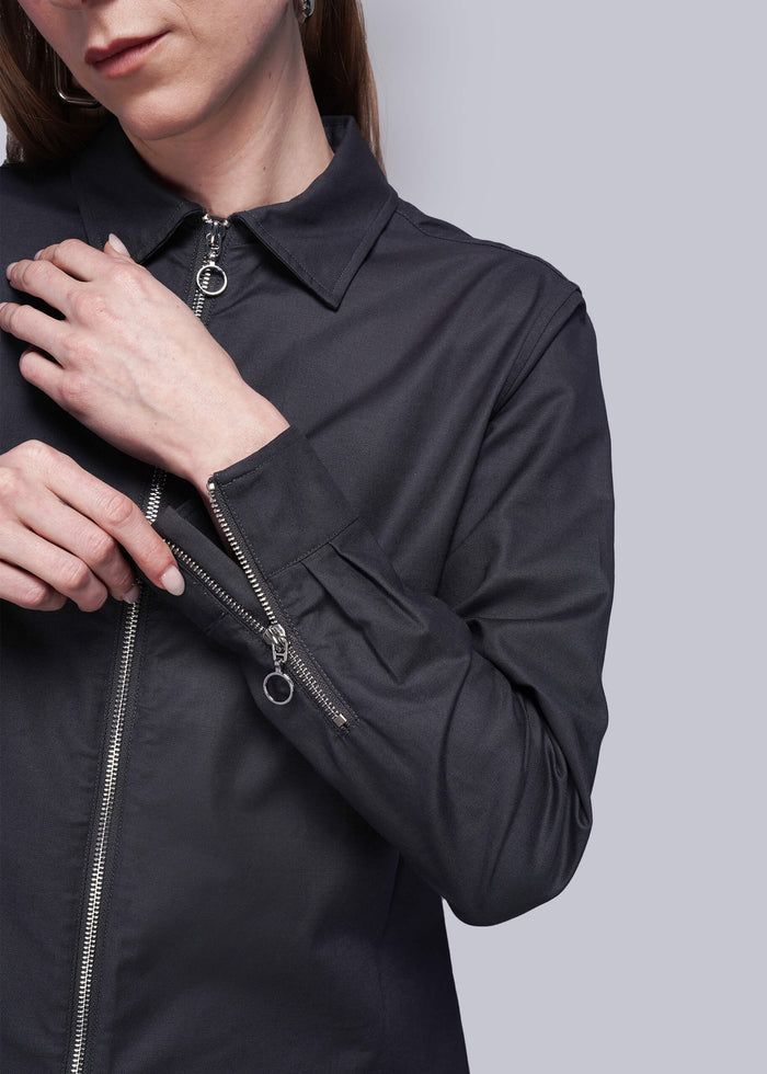 S=Close up of person wearing a black zip up shirt showing zipper detail on cuffs
