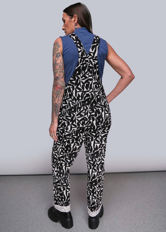 S=Person wearing a black and white patterned jumpsuit with a blue top against a gray background