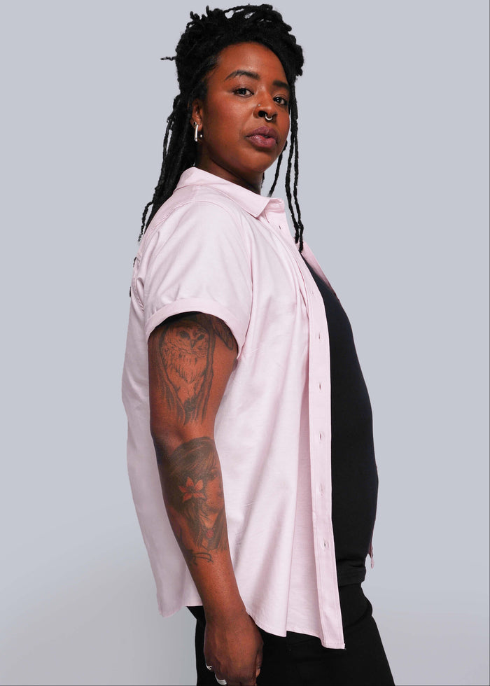 1X=Person wearing a light pink shirt over a black top against a plain background