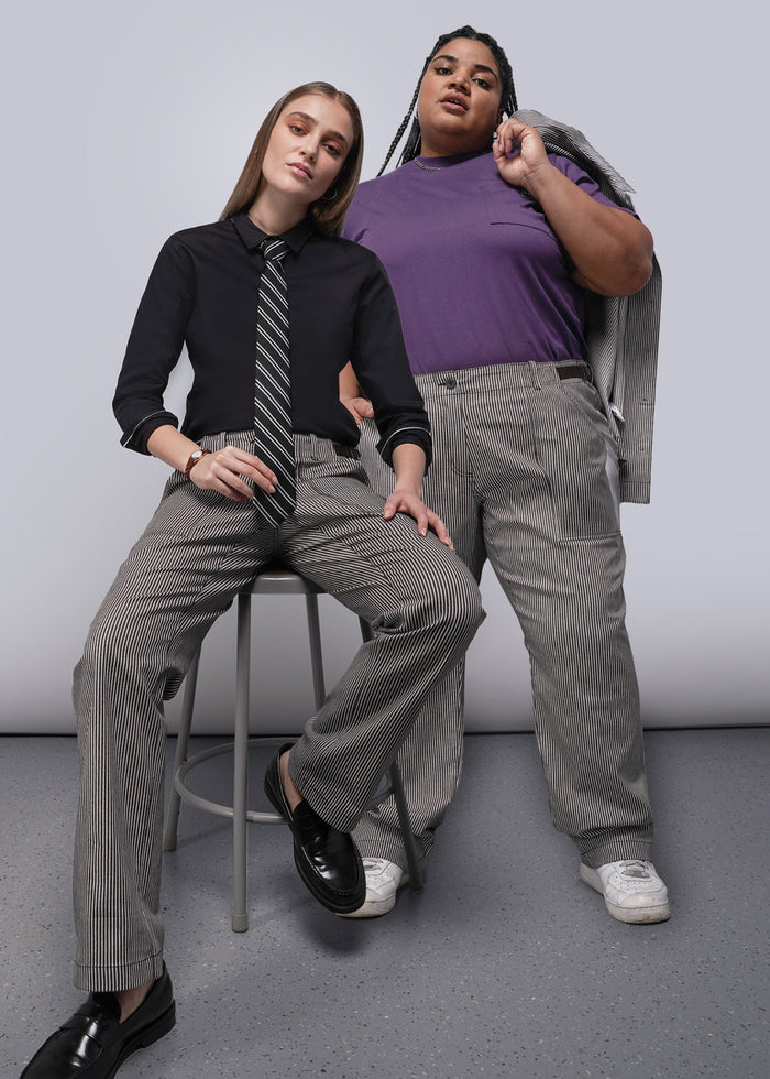 Two people wearing brown and white striped pants against a plain background