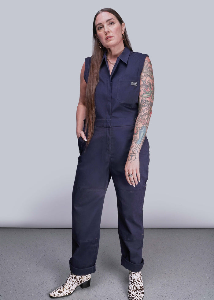 S=Woman wearing a navy blue sleeveless jumpsuit on a plain background