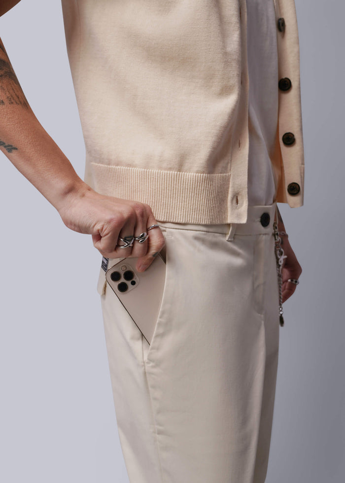 S=Person wearing a beige vest and pants with a plain background