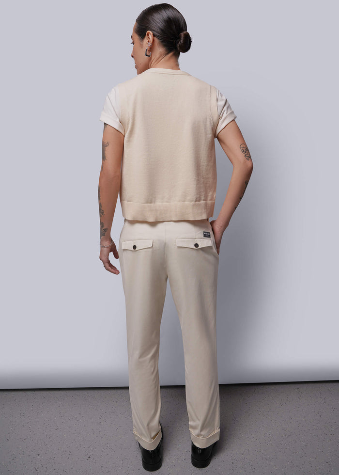 S=Person wearing a beige vest and pants standing against a plain background