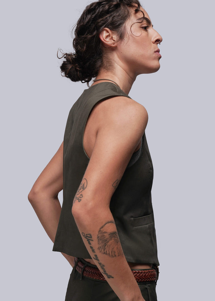 S=Person wearing a sleeveless green vest against a plain background