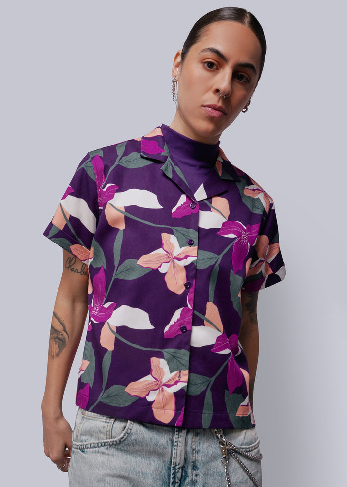 S=Person wearing a purple floral shirt against a plain background