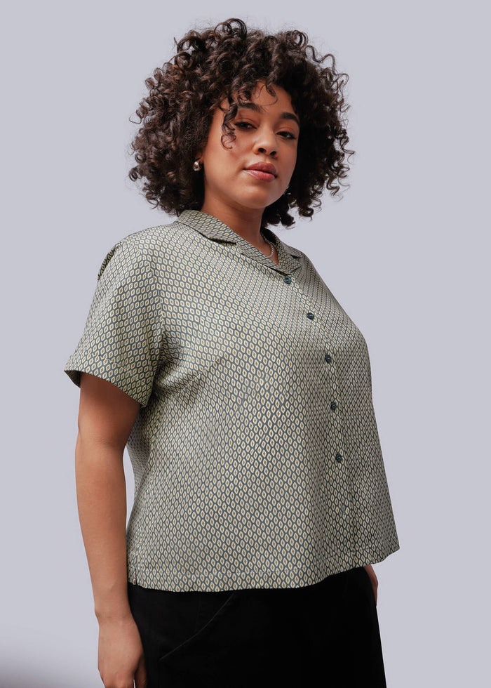 1X=Woman wearing a patterned blouse against a plain background
