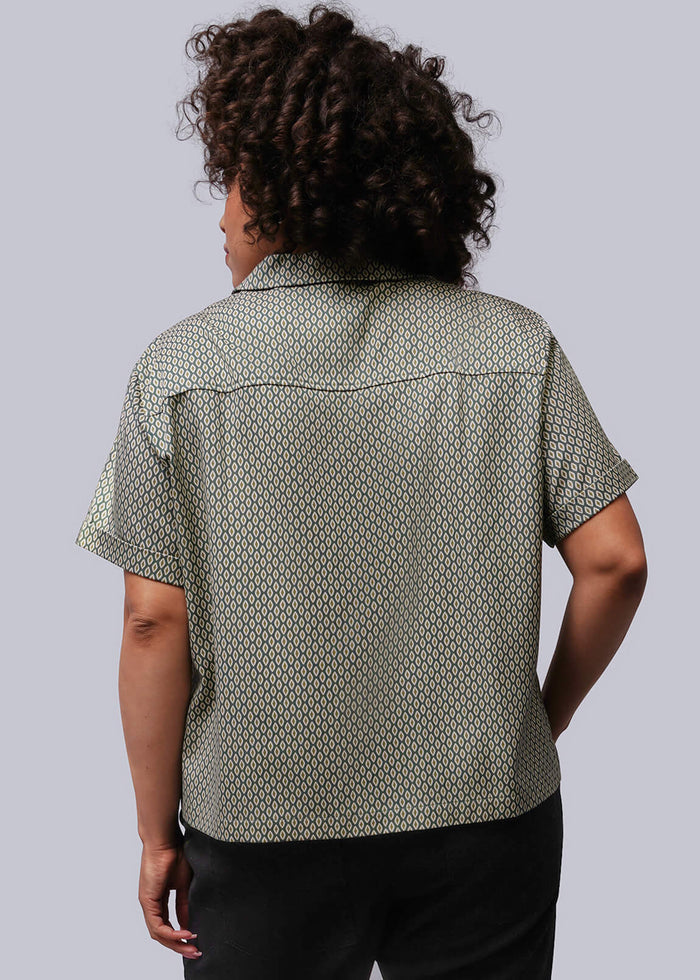 1X=Person wearing a patterned shirt and black pants against a plain background