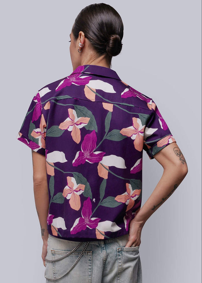 S=Person wearing a purple floral shirt and light blue jeans against a white background
