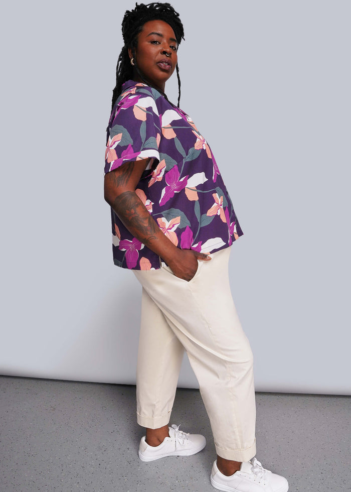 1X=Person wearing a colorful floral shirt and beige pants against a plain background