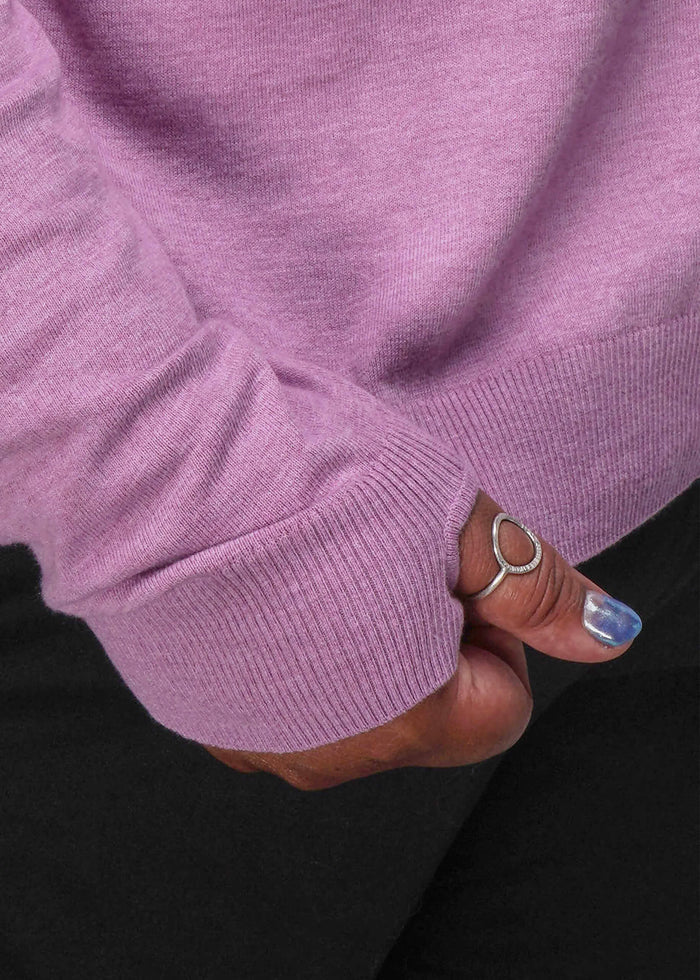 1X=Close-up of a person wearing a pink sweater with a black background