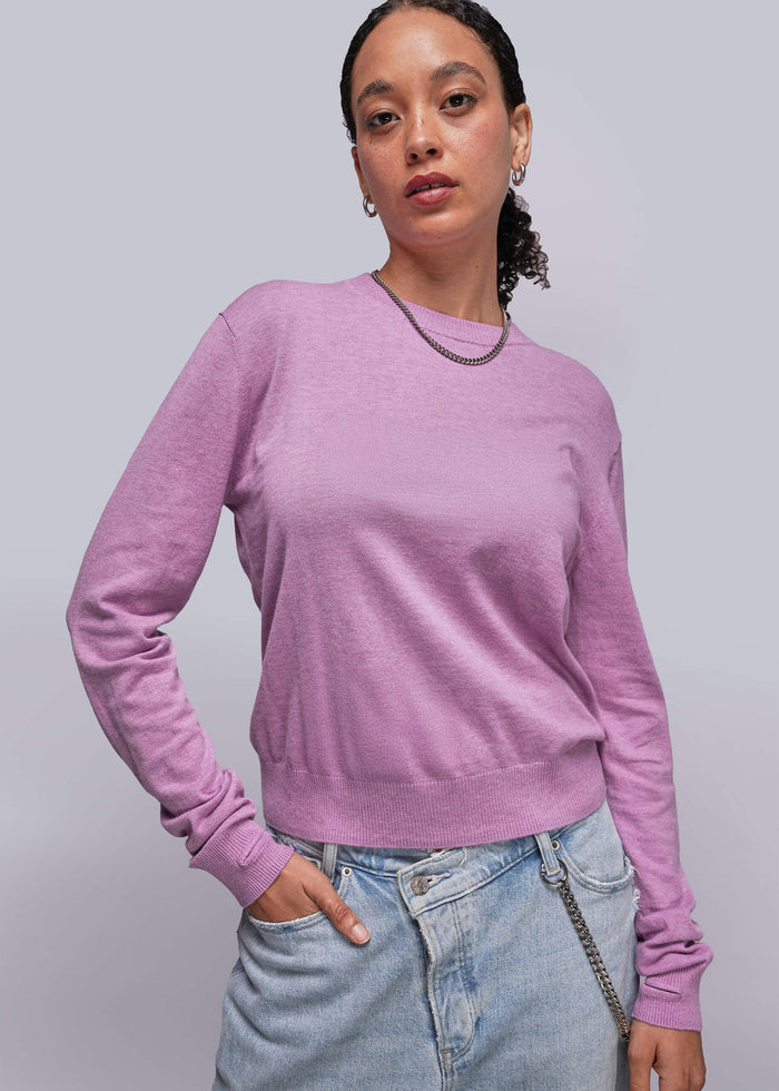 S=Person wearing a pink sweater and light blue jeans against a plain background