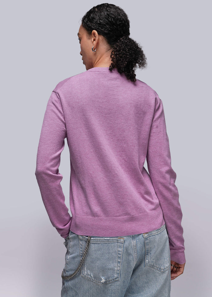S=Person wearing a pink toned sweater and light blue jeans against a plain background