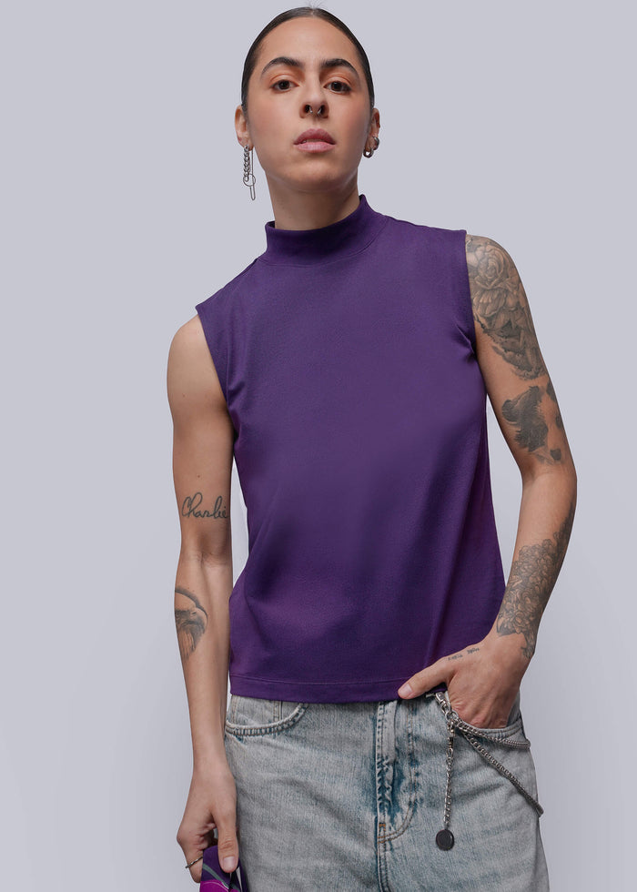 S=Person wearing a purple sleeveless top and jeans on a plain background