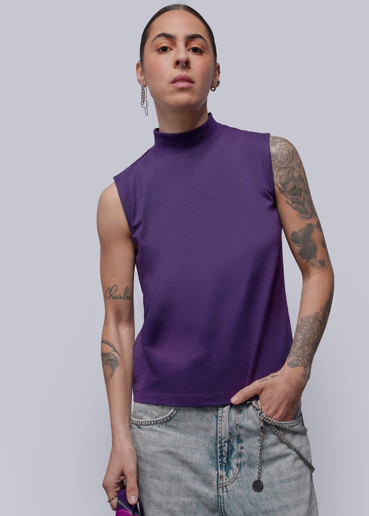 S=Person wearing a purple sleeveless top and jeans on a plain background