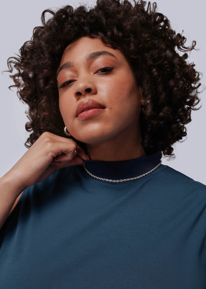 1X=Person wearing a blue top with a plain background