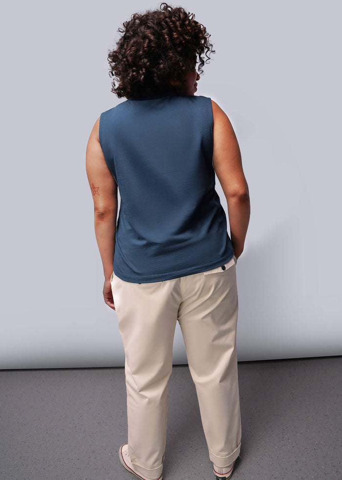 1X=Person wearing a blue sleeveless top and beige pants against a plain background