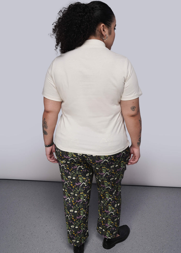 1X=Back of person wearing a white shirt and patterned pants against a plain background