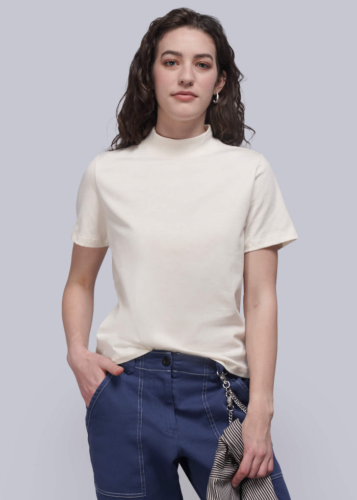 S=Woman wearing a white t-shirt and blue pants holding a striped blazer against a plain background