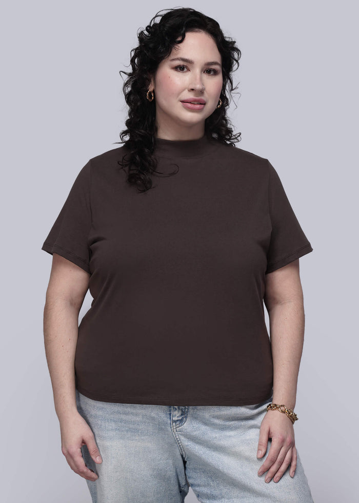 1X=Person wearing a brown t-shirt and light blue jeans against a plain background