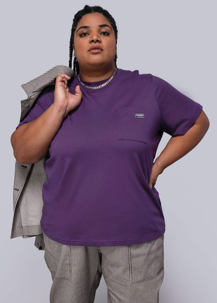 1X=Person wearing a purple shirt and gray pants against a plain background