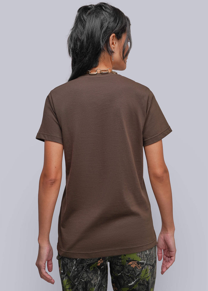 S=A woman shown from the back wearing a solid brown short-sleeve t-shirt and camouflage pants, photographed against a solid light gray background.