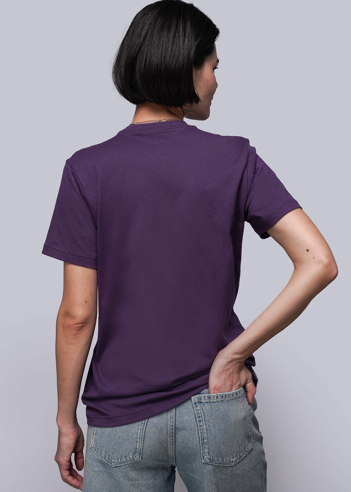 S=Person wearing a purple t-shirt and gray pants against a plain background