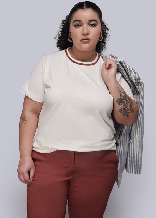 1X=Person wearing a white t-shirt with red trim and maroon pants, holding a gray jacket.