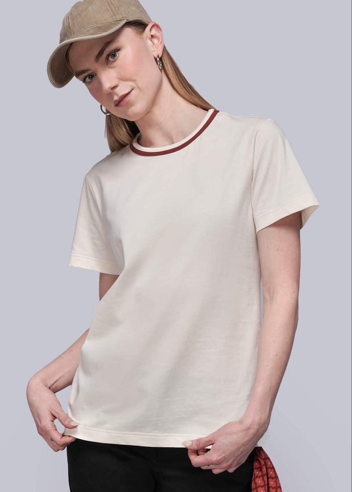 S=Person wearing a beige t-shirt, black pants, and a cap on a plain background