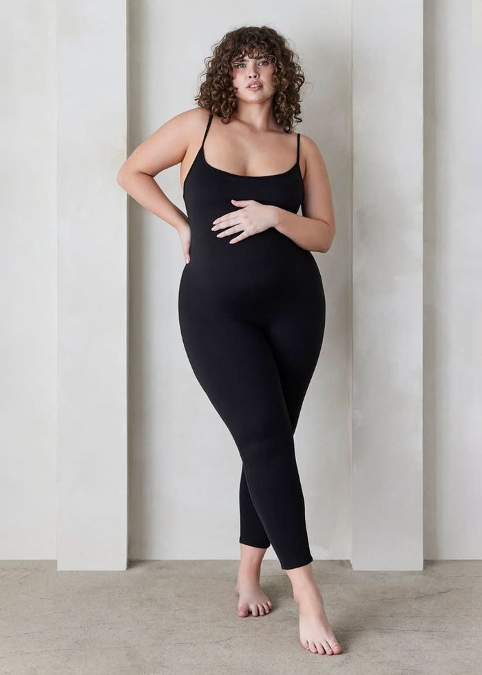 a woman wearing the kate maternity spaghetti strap full length sleeveless jumpsuit in black