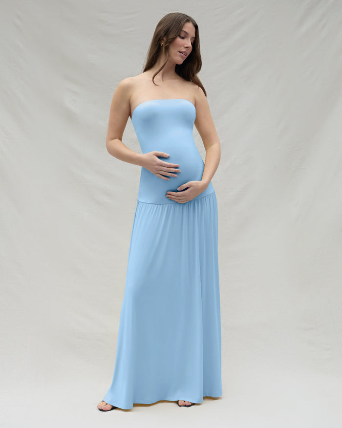 Pregnant woman wearing a powder blue strapless maternity gown against a plain background