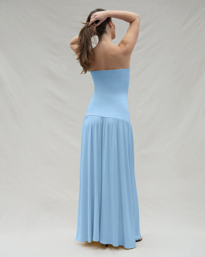 Back view of a woman wearing a powder blue strapless gown against a plain background
