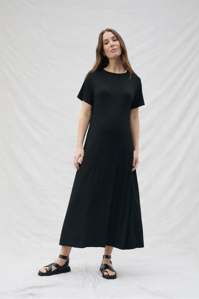 Pregnant woman wearing a black dress against a white background