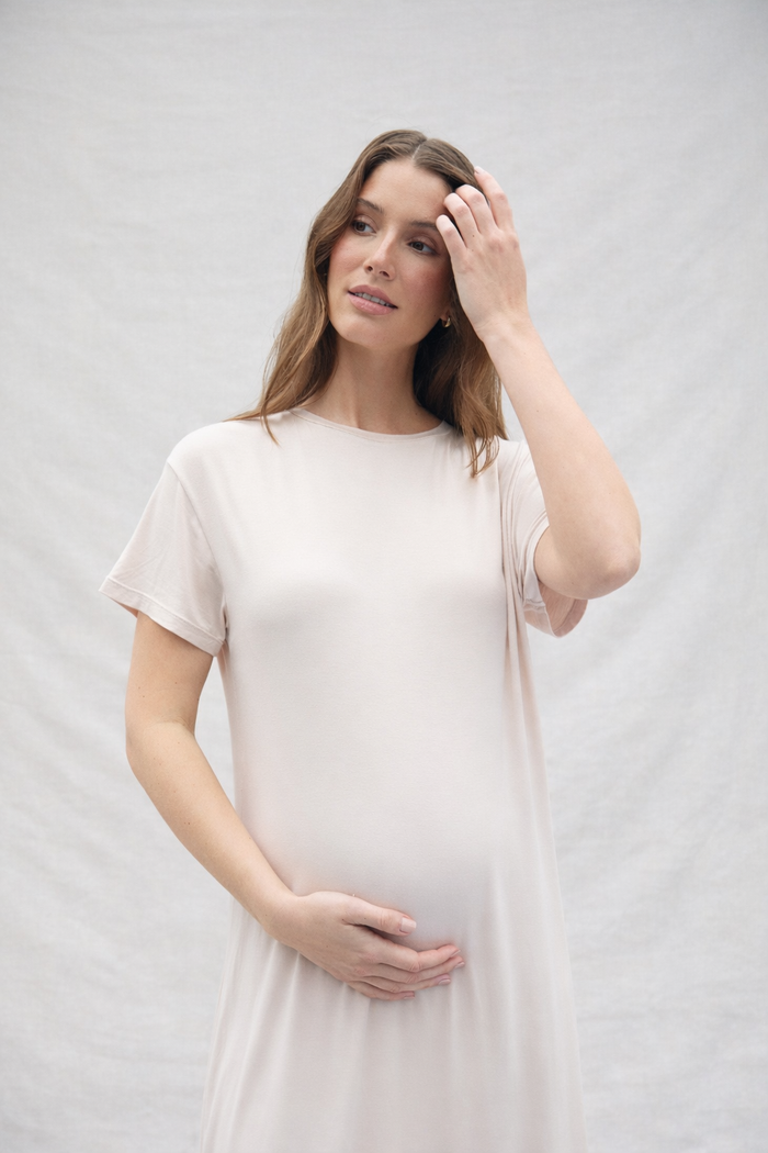 Woman wearing a oat coloured cotton dress against a plain background